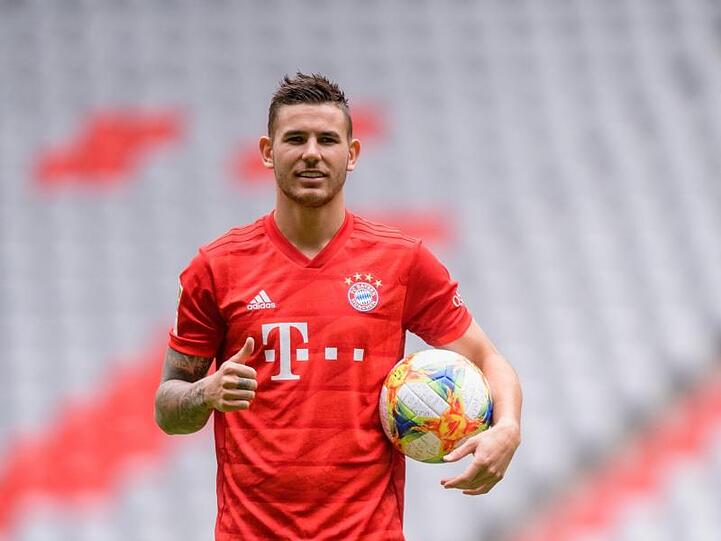 Lucas Hernandez vom FC Bayern München steht in der Allianz Arena auf dem Spielfeld und hält einen Fußball in der linken Hand, während er mit dem rechten Daum nach oben zeigt. Foto: Matthias Balk