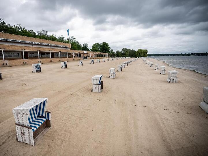 Auch in Berlin darf wieder geurlaubt werden - und wer mag, kann sich trotz Regen ins Strandbad Wannsee wagen.