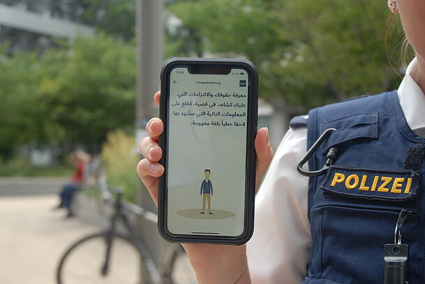 Eine Polizistin führt die App FLAP vor, hier mit einem Anwendungsbeispiel auf Arabisch. Parallel zur Audio-Ansage kann man also als angesprochener Arabisch-Muttersprachler mitlesen.