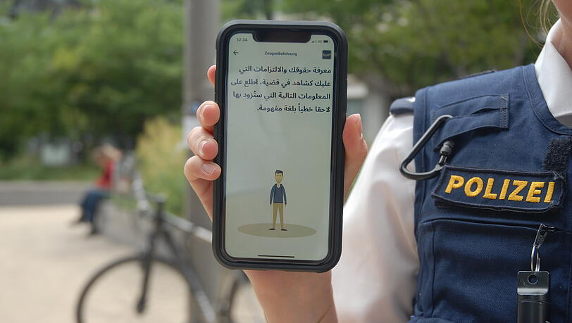 Eine Polizistin führt die App FLAP vor, hier mit einem Anwendungsbeispiel auf Arabisch. Parallel zur Audio-Ansage kann man also als angesprochener Arabisch-Muttersprachler mitlesen. Eine Polizistin führt die App FLAP vor, hier mit einem Anwendungsbeispiel auf Arabisch. Parallel zur Audio-Ansage kann man also als angesprochener Arabisch-Muttersprachler mitlesen.