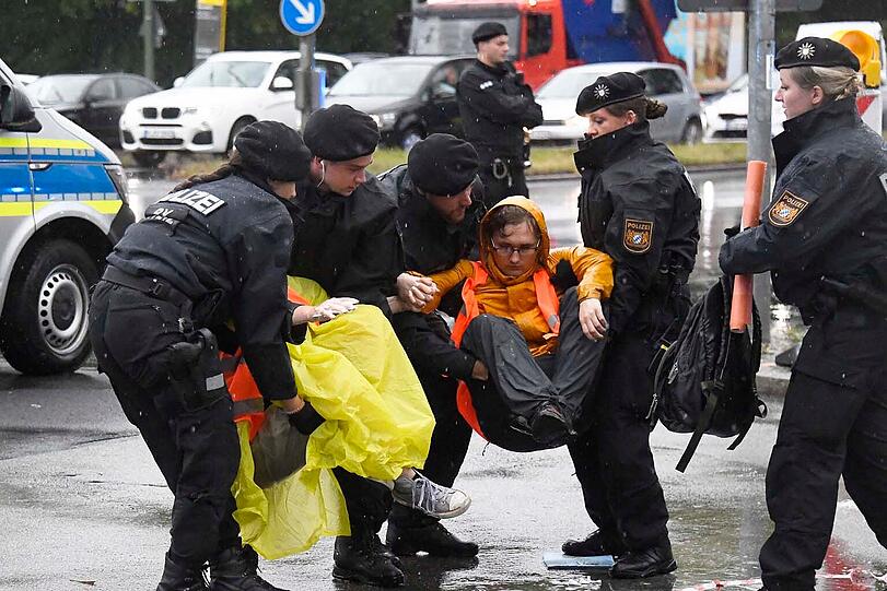 Polizisten tragen Klima-Aktivisten von der Straße.