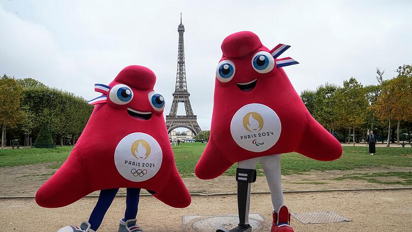 Die Maskottchen der Olympischen (l) und Paralympischen Spiele in Paris stehen vor dem Eiffelturm.