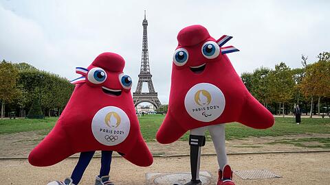 Die Maskottchen der Olympischen (l) und Paralympischen Spiele in Paris stehen vor dem Eiffelturm.