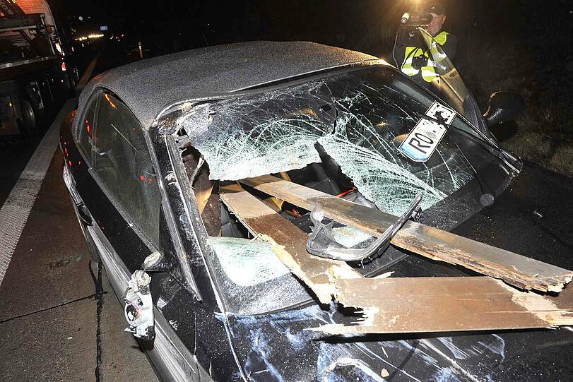 Holzbretter haben sich in den BMW hineingebohrt. Dessen Fahrer bleibt wundersamerweise unverletzt.