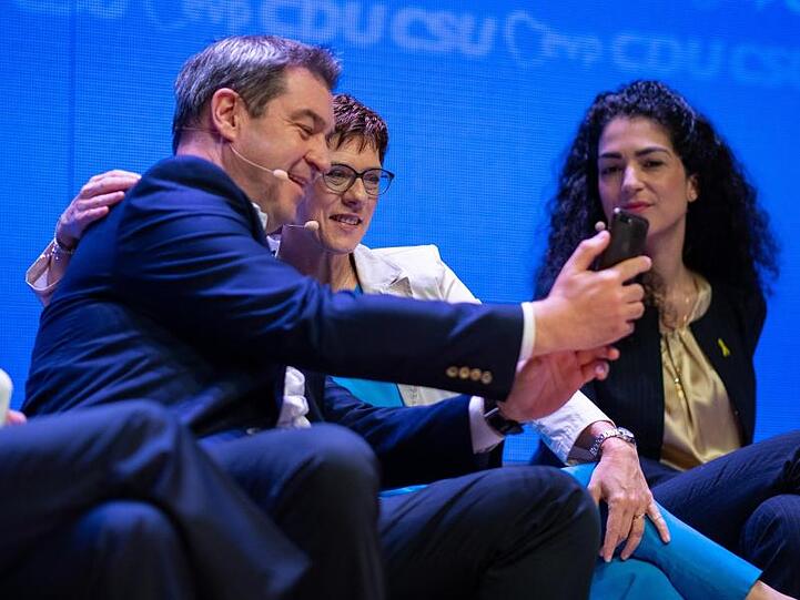 Markus Söder (CSU, l) und Annegret Kramp-Karrenbauer (CDU, M) machen auf der Bühne ein Selfie. Foto: Guido Kirchner