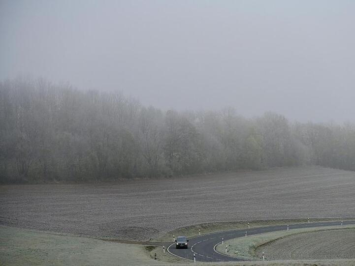 Ein Auto fährt durch eine verregnete Landschaft. Foto: Frank May/dpa
