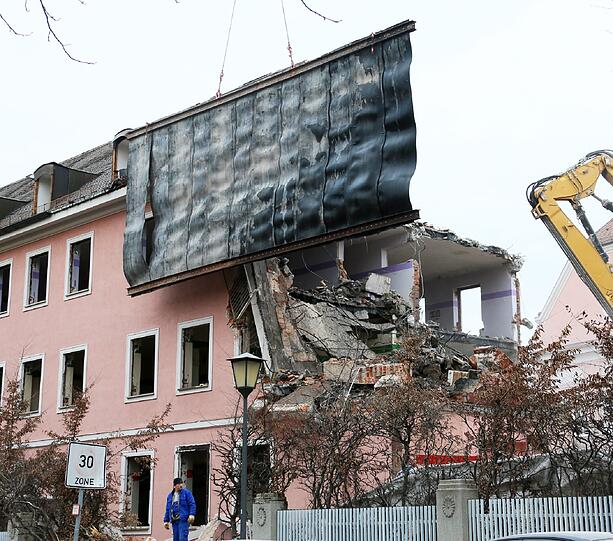 Ein weiterer Bagger hält eine Abriss-Plane, damit niemand durch Trümmer verletzt wird.