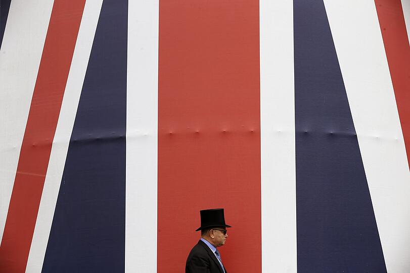 Ein Gast des Pferderennens geht an einer riesigen britischen Flagge vorbei.