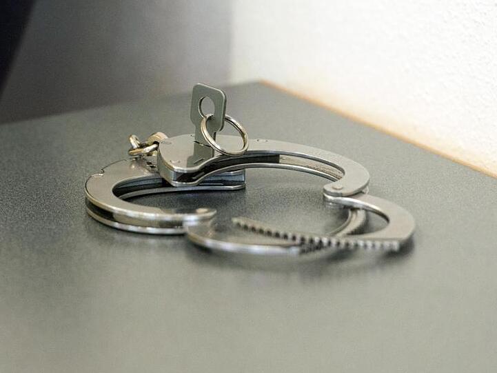 Handschellen liegen auf einem Tisch. Foto: Armin Weigel/dpa/Symbolbild