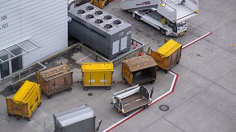 Gepäckwagen stehen am Flughafen München auf dem Rollfeld: Viele Fluggäste warten eine Woche nach ihrem Zwischenstopp in München noch immer auf ihr Gepäck.