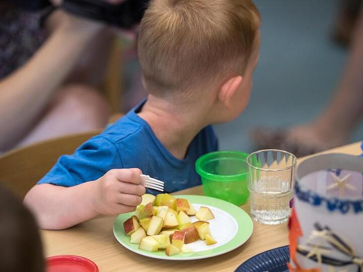 Ein Kind isst in einer Kita Apfelstücke. Foto: Andreas Arnold/Archivbild