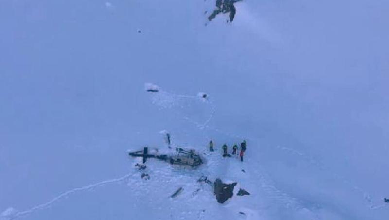 Eine Gruppe von Bergrettern stehen neben den Trümmern des Hubschraubers. Eine Gruppe von Bergrettern stehen neben den Trümmern des Hubschraubers.