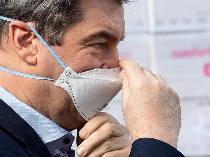 CSU-Chef Söder Markus Söder zieht sich einen Mundschutz über sein Gesicht. Foto: Sven Hoppe/dpa