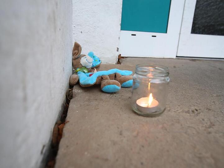 Ein Teddy liegt neben einem Teelicht im Eingangsbereich eines Wohnhauses im Stadtteil Winzerla.