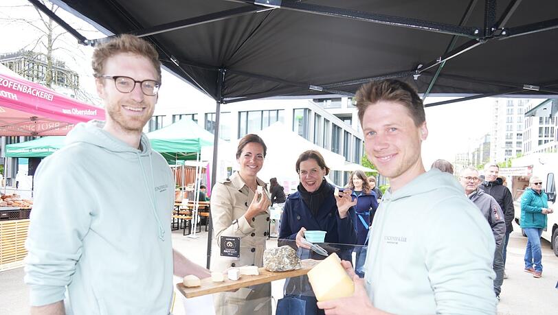 Kristina Frank (Mitte links) und Verena Dietl (Mitte rechts) probieren die Spezialitäten der Münchner Käsemanufaktur. Für die beiden Produzenten Johannes (links) und Sebastian (rechts) ist es das erste Mal, dass sie ihren Käse auf einem Markt verkaufen.