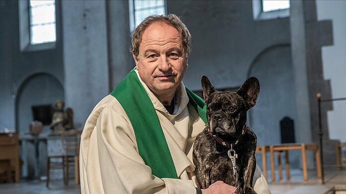 Pfarrer Rainer Maria Schießler mit seiner Hündin Pia in der St. Maximilian Kirche in München.