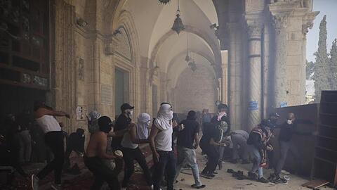 Vermummte Palästinenser werfen mit Steinen auf israelische Sicherheitskräfte.