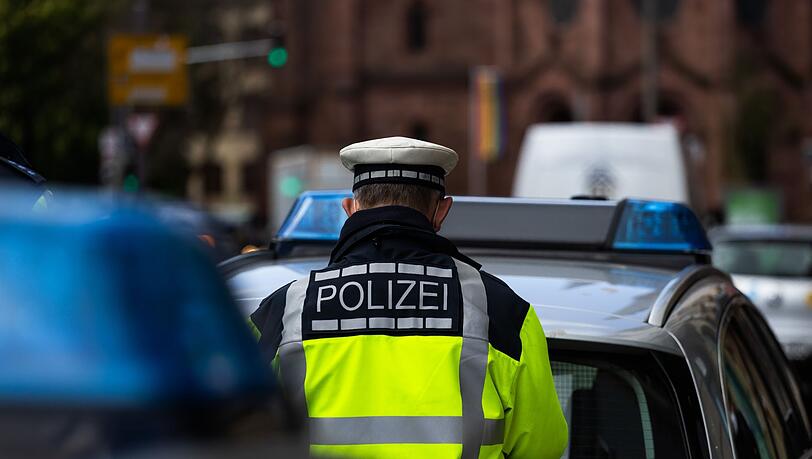Ein Polizeibeamter steht zwischen zwei Einsatzfahrzeugen der Polizei.