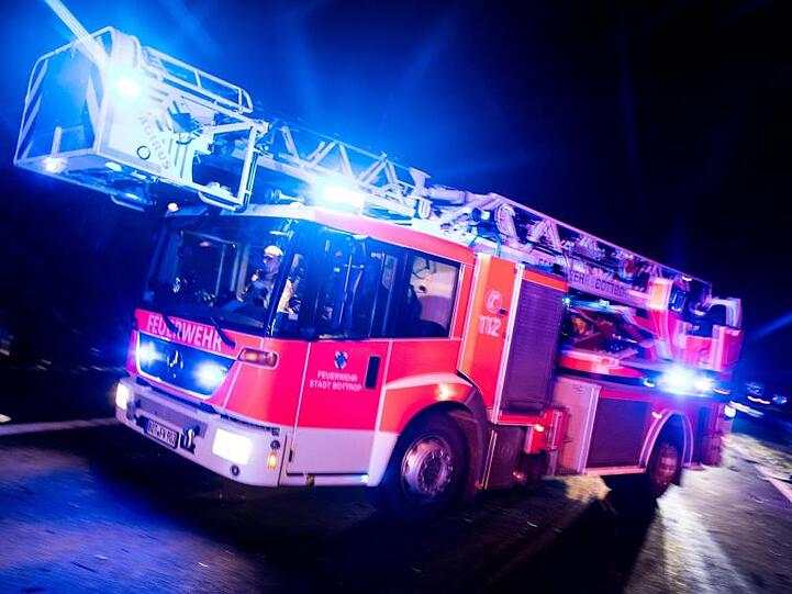 Ein Drehleiterwagen der Feuerwehr fährt mit Blaulicht an einer Unfallstelle vorbei. Foto: Marcel Kusch/dpa/Illustration