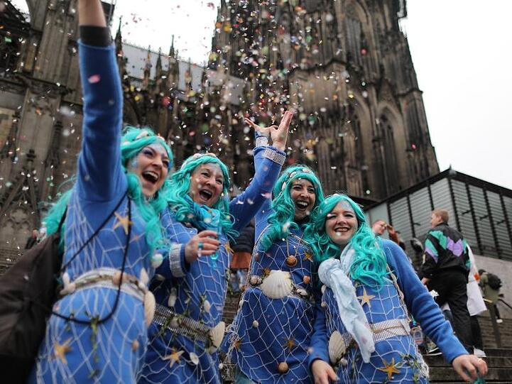 Eine Frauengruppe in Blau wirft Konfetti vor dem Kölner Dom.