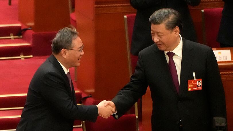 Chinas Staats- und Parteichef Xi Jinping (r) wird von Ministerpräsident Li Qiang beglückwünscht, nachdem er erneut einstimmig zum Präsidenten gewählt wurde.