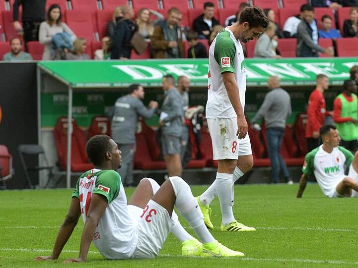 Reece Oxford(l-r), Rani Khedira und Ruben Vargas vom FC Augsburg sitzen und stehen auf dem Rasen. Foto: Stefan Puchner/dpa/Archivbild