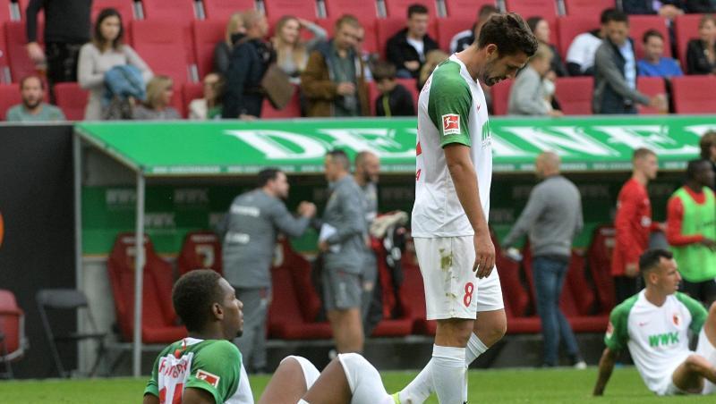 Reece Oxford(l-r), Rani Khedira und Ruben Vargas vom FC Augsburg sitzen und stehen auf dem Rasen. Foto: Stefan Puchner/dpa/Archivbild Reece Oxford(l-r), Rani Khedira und Ruben Vargas vom FC Augsburg sitzen und stehen auf dem Rasen. Foto: Stefan Puchner/dpa/Archivbild
