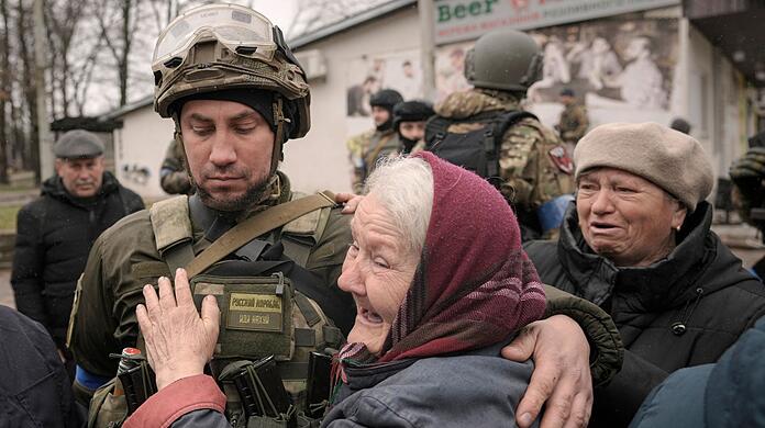 Eine Frau umarmt einen ukrainischen Soldaten, nachdem ein Konvoi von Militär- und Hilfsfahrzeugen in dem ehemals russisch besetzten Kiewer Vorort Butscha eingetroffen ist.