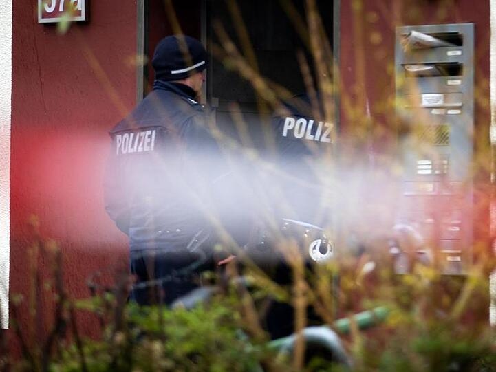 Polizeibeamte bewachen den Eingang eines Hauses, im Vordergrund flattert Polizeiabsperrband. In einer der Wohnungen wurden zwei tote Kleinkinder im Alter von ein und zwei Jahren gefunden worden.