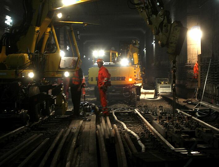 Mit zwei Baggern werden die alten Schienen und Schwellen herausgeholt und die neuen an ihrer Plätze gebracht. Die Luft im Tunnel ist zum Schneiden.