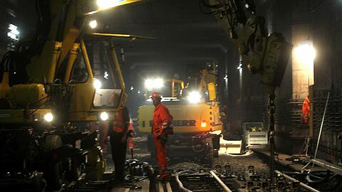 Mit zwei Baggern werden die alten Schienen und Schwellen herausgeholt und die neuen an ihrer Plätze gebracht. Die Luft im Tunnel ist zum Schneiden.