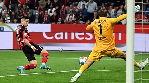 Leverkusens Paulinho (l) erzielt das 1:0 gegen Frankfurts Torhüter Kevin Trapp .