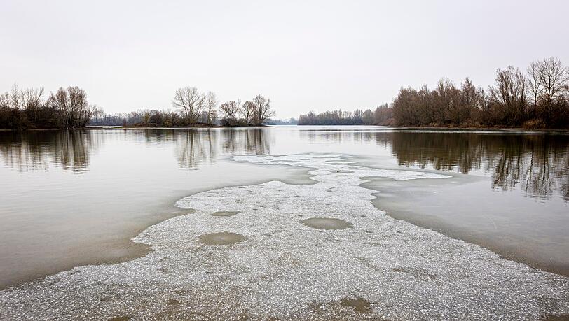 Eine dünne Eisschicht bedeckt bei trübem Wetter die Wasseroberfläche der Koldinger Seen in der Region Hannover.