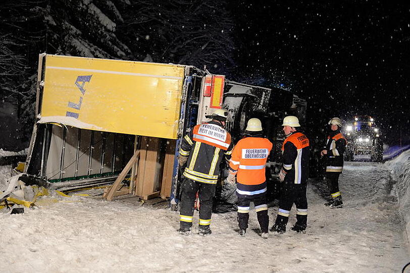 Ein LKW kommt auf schneeglatter Fahrbahn ins Rutschen und kippt um