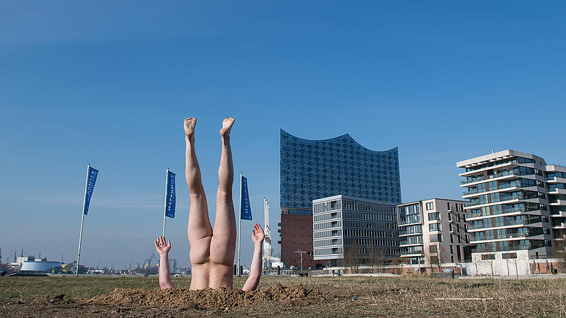 Steckt den Kopf in den Sand: Der russische Konzeptkünstler Andrey Kuzkin vor der Elbphilharmonie.