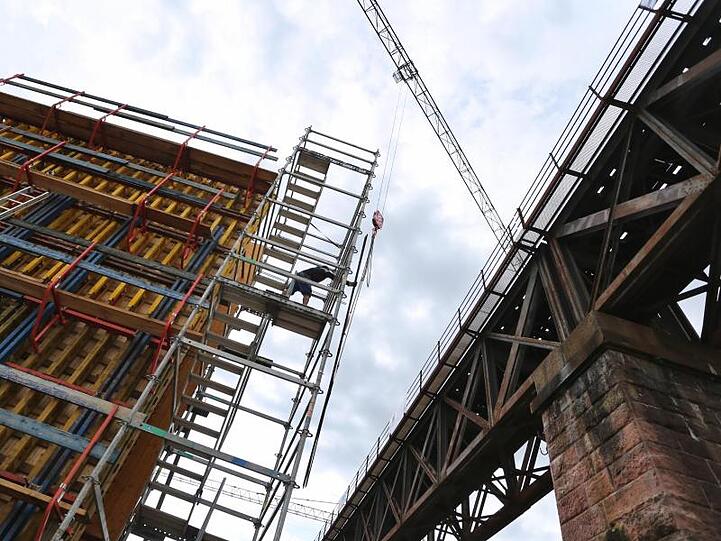 Ein Bauteil einer Eisenbahnbrücke wird von einem Kran auf ein Fundament gehoben. Foto: Karl-Josef Hildenbrand/dpa/Archivbild