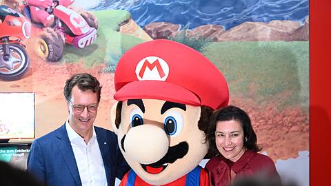 Beim Messerundgang über die Gamescom kam der Tross von Politikern auch beim Messestand von Nintendo vorbei, hier stehen NRW-Ministerpräsident Hendrik Wüst (CDU) und Bundesforschungsministerin Dorothee Bär (CSU) neben einer Mario-Plüschfigur.