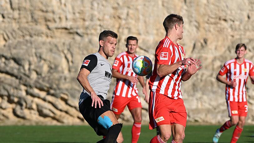 Der Augsburger Florian Niederlechner (l) spielt gegen Kevin Behrens von Union Berlin den Ball.