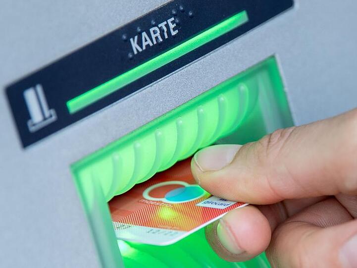 Eine Bankkundin steckt ihre Girokarte in einen Geldautomaten.