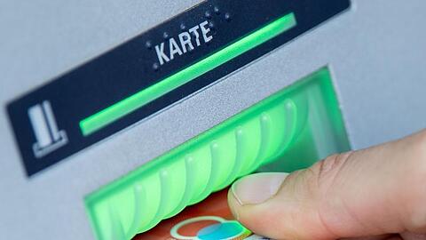 Eine Bankkundin steckt ihre Girokarte in einen Geldautomaten.