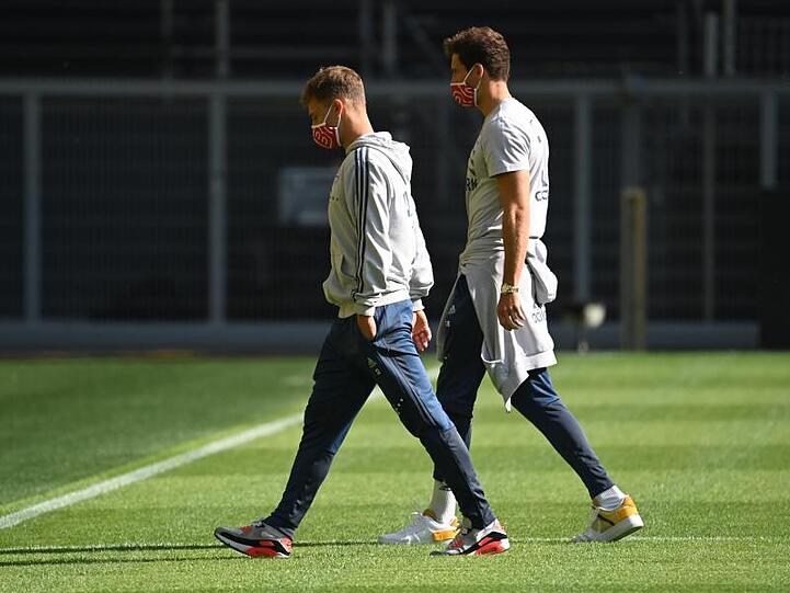 Münchens Kimmich (l.) und Goretzka gehen mit Mundschutz über das Spielfeld vor Spielbeginn. Foto: Federico Gambarini/dpa-Pool/dpa
