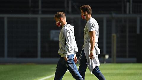 Münchens Kimmich (l.) und Goretzka gehen mit Mundschutz über das Spielfeld vor Spielbeginn. Foto: Federico Gambarini/dpa-Pool/dpa