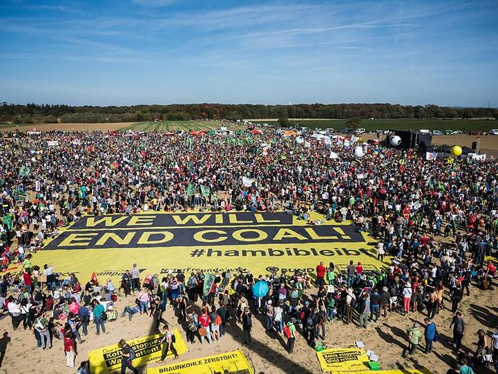Teilnehmer der Demonstration zum Thema "Wald retten! Kohle stoppen!" stehen auf einem Acker neben dem Hambacher Wald.