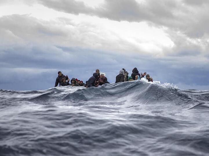 Männer aus Marokko und Bangladesch in einem überfüllten Holzboot vor der Küste von Libyen.