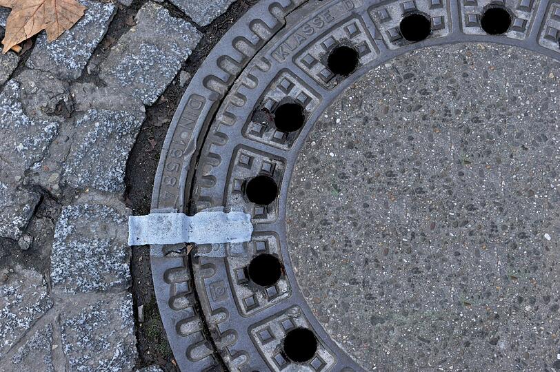 Die Polizei fahndet nach einem Unbekannten, der zwei Gullydeckel vom Dach eines Parkhauses auf die Straße warf. (Symbolbild)
