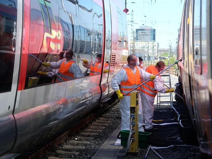 Graffiti-Entferner arbeiten am Leipziger Hauptbahnhof an besprühten S-Bahnwagen.