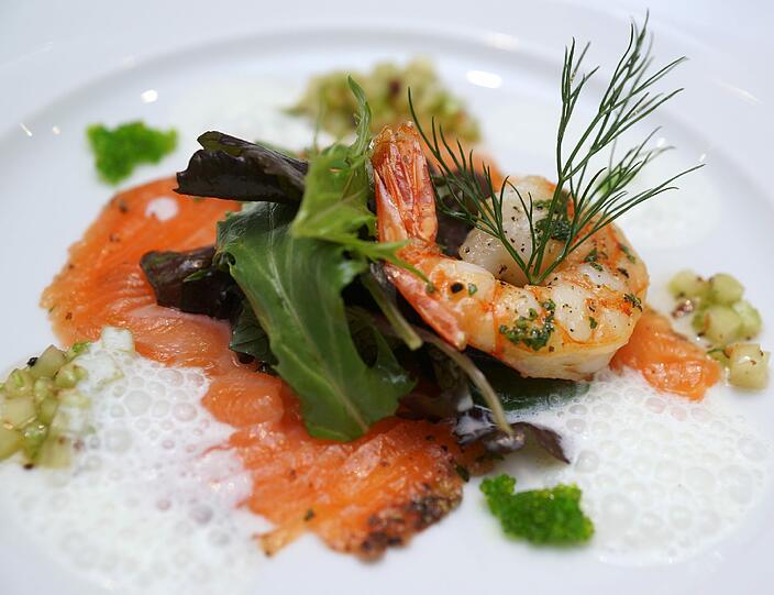 Gang 1: Gebratener Scampi und Carpaccio vom gebeizten Citruslachs mit Tobiko-Kaviar auf Wildkräutersalat und Gurkensalsa