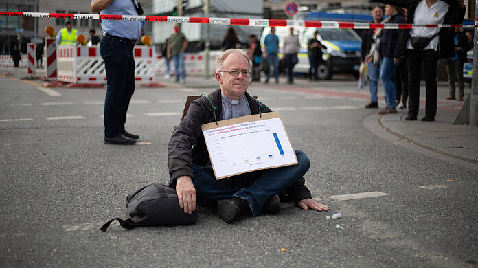 Jesuitenpater Jörg Alt bei seinem Klebe-Protest am Stachus im vergangenen Oktober.