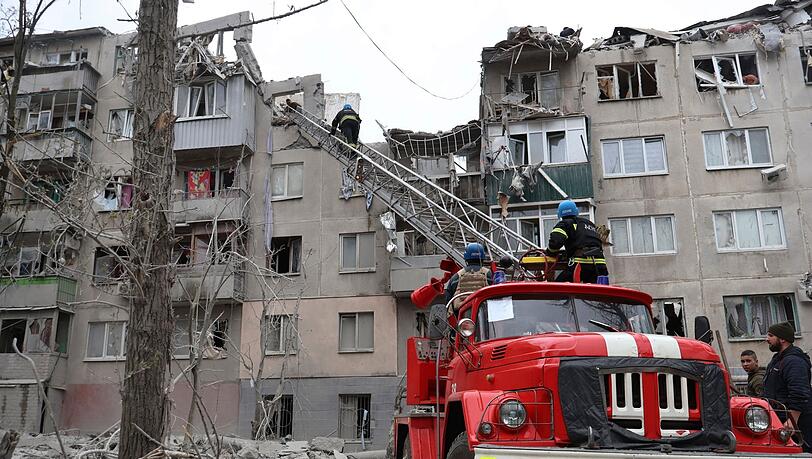Feuerwehrleute arbeiten daran, ein Feuer zu löschen, während sie nach einem Raketenangriff nach möglichen Opfern suchen.