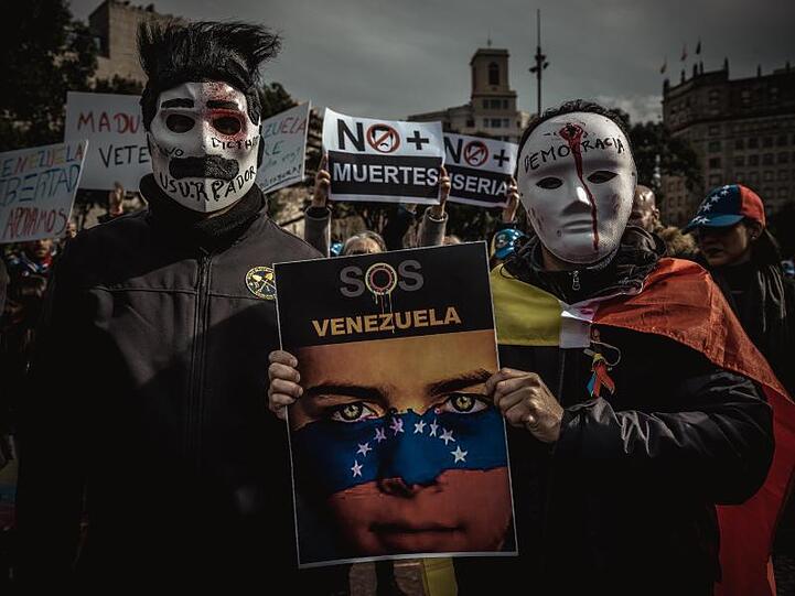 Maduro-kritische Demonstranten tragen bei einem Protestmarsch in Barcelona Masken.